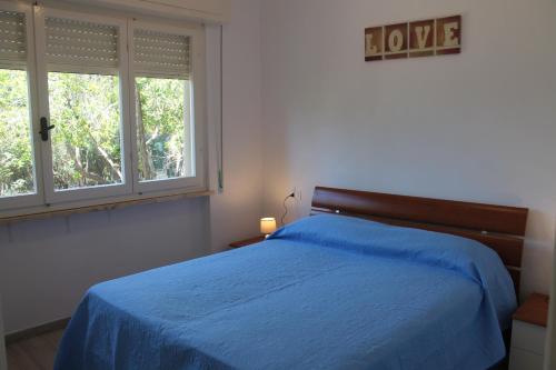 1 dormitorio con 1 cama azul y 2 ventanas en Le tre caravelle S Maria a soli 150m dal mare -WI-FI en Marina di Castagneto Carducci