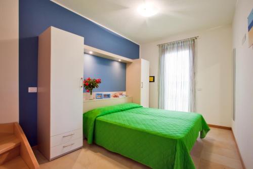 Un dormitorio con una cama verde y una pared azul en Villaggio Laguna Blu, en Caorle
