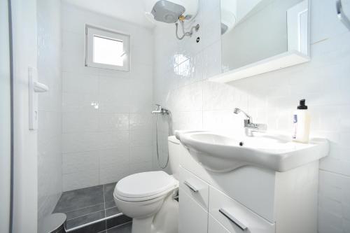 a white bathroom with a toilet and a sink at Apartmani Bonik in Budva
