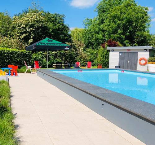 a swimming pool with an umbrella and a table and chairs at Novotel Rotterdam - Schiedam in Schiedam