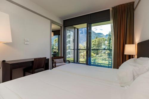 a hotel room with a bed and a large window at Du Lac Et Du Parc Grand Resort in Riva del Garda
