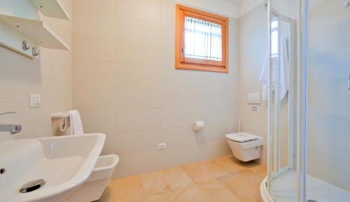 baño con lavabo y aseo y ventana en Villaggio Laguna Blu, en Caorle