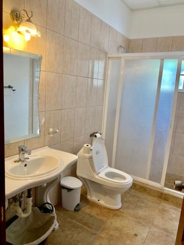 a bathroom with a white toilet and a sink at Chupaflor - Alexander Luxury & Executive Suites in Belize City