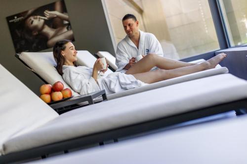 a man and a woman laying on beds in a room at Du Lac Et Du Parc Grand Resort in Riva del Garda