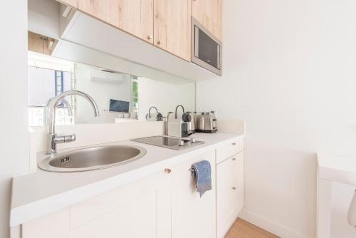 - une cuisine blanche avec un évier et un miroir dans l'établissement Place Du Pin, à Nice