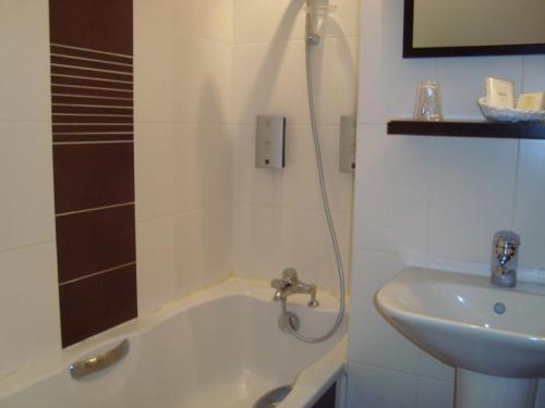 a bathroom with a bath tub and a sink at Hôtel de La Croix d'Or in Avranches