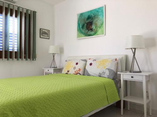 - une chambre avec un lit vert et 2 tables de chevet dans l'établissement Pissouri Beach Front Apartments, à Pissoúri