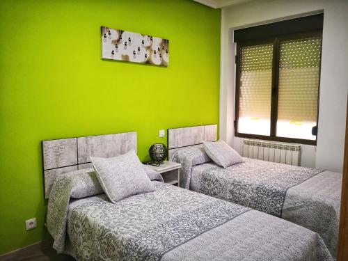 2 camas en una habitación con una pared verde en Apartamentos Cocó, en Ávila