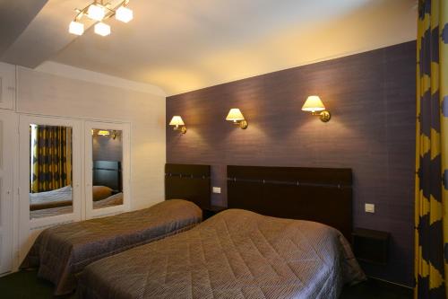 a hotel room with two beds and lights on the wall at Hôtel de La Croix d'Or in Avranches