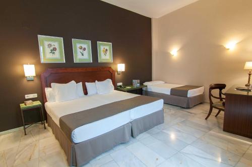 a hotel room with two beds and a desk at Hotel San Gil in Seville