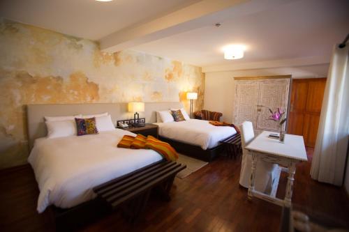 a hotel room with two beds and a table at Tocuyeros Boutique Hotel in Cusco