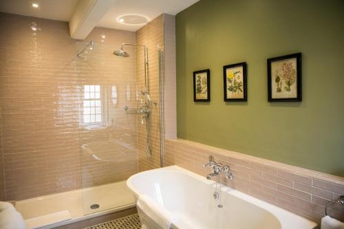 a bathroom with a tub and a shower and a sink at Leeds Castle Stable Courtyard Bed and Breakfast in Maidstone