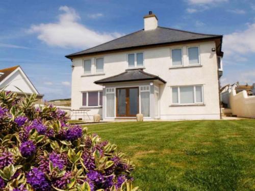 a large white house with purple flowers in the yard at Holiday Home Tully Hip by Interhome in Towyn