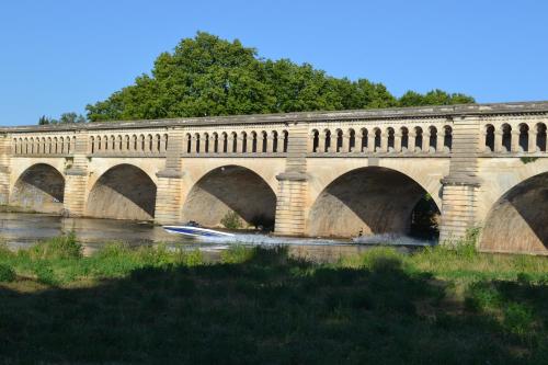 a bridge over a river with a boat in the water at L'instant Canal in Capestang