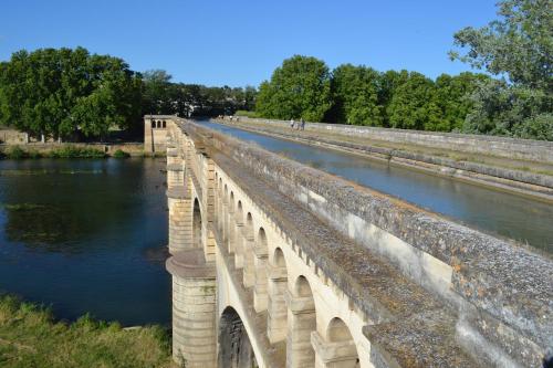 a bridge over a river next to a body of water at L'instant Canal in Capestang