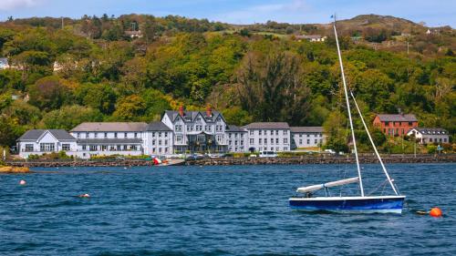 un velero flotando en el agua frente a una ciudad en Eccles Hotel and Spa, en Glengarriff