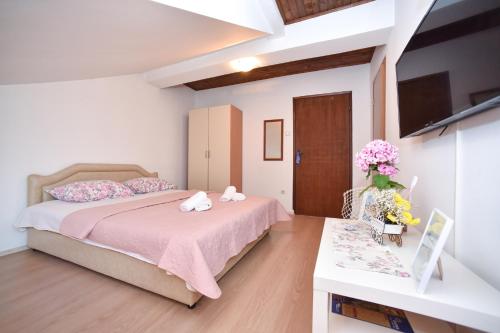ein Schlafzimmer mit einem Bett und einem Tisch mit Blumen in der Unterkunft Apartmani Bonik in Budva