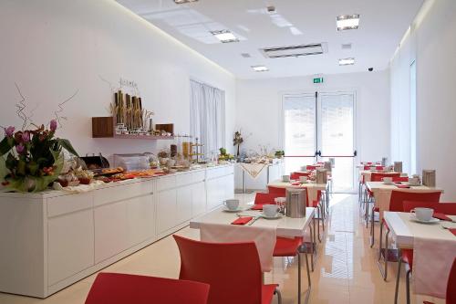 a restaurant with tables and red chairs and a buffet at Card International Hotel in Rimini