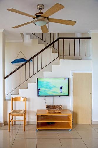 a living room with a tv and a staircase at 9 Seesonnet Scottburgh in Scottburgh
