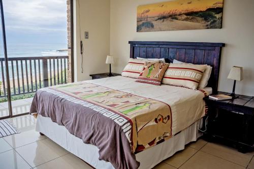 a bedroom with a large bed and a balcony at 9 Seesonnet Scottburgh in Scottburgh