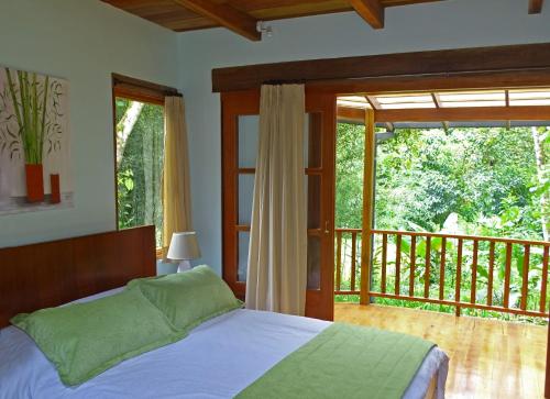 1 dormitorio con 1 cama y balcón en Sacha Urco Lodge y Bosque Protector, en Mindo