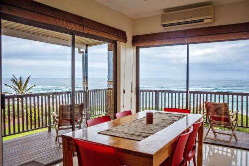 a dining room with a table and chairs and the ocean at 9 Seesonnet Scottburgh in Scottburgh