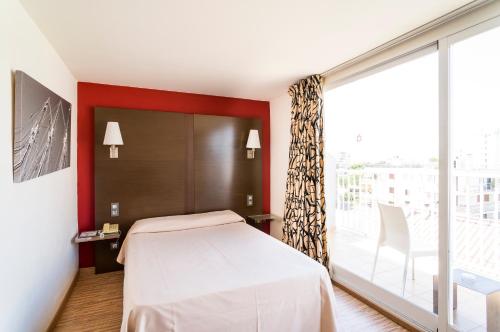 a bedroom with a bed and a large window at Nautic Hotel & Spa in Can Pastilla