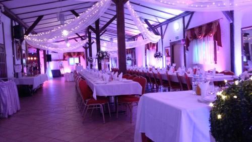 a dining room with white tables and chairs and lights at Zajazd Eljan-Centrum Noclegowe in Olsztyn