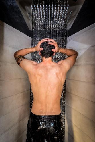 a shirtless man in a shower with his hands on his head at Hotel La Sorgente in Tesero