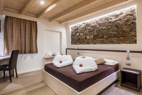 a room with a bed with white pillows on it at Hotel La Sorgente in Tesero