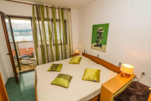 Un dormitorio con una cama con almohadas amarillas y una ventana en Apartments Andrea, en Baška