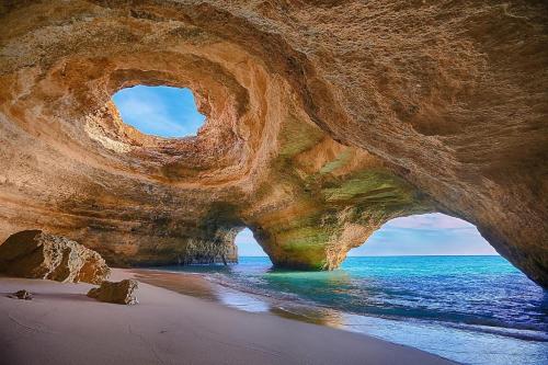 a large rock formation on a beach with the ocean at Rocha Brava Village Resort in Carvoeiro