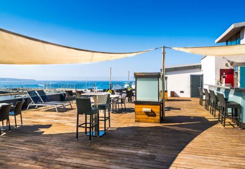 a wooden deck with chairs and tables and the ocean at Nautic Hotel & Spa in Can Pastilla