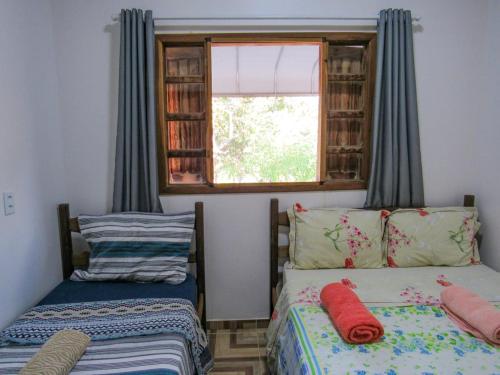 une chambre avec deux lits et une fenêtre dans l'établissement Chácara Recanto das Pedras, à Cavalcante