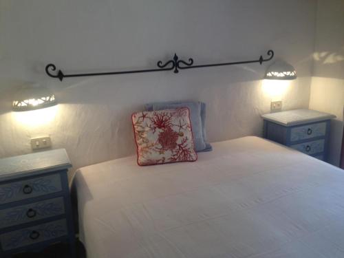 una camera con un letto con due cassettiere e un cuscino di Il Melograno Cannigione Villaggio Gallura a Cannigione