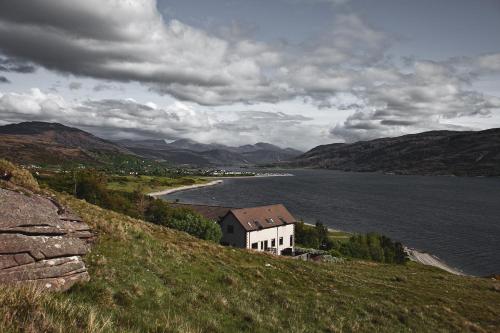 a house on a hill next to a body of water at Ardvreck House in Ullapool