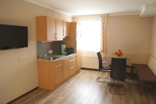 eine kleine Küche mit einem Waschbecken und einem Tisch mit Stühlen in der Unterkunft Apartments Hartsleben in Flachau