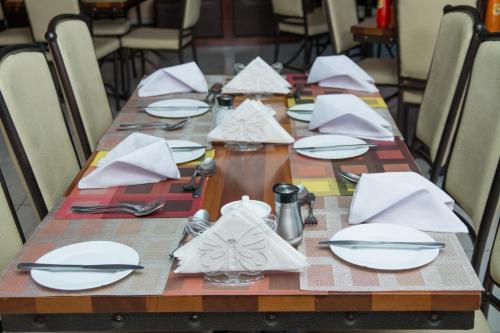 a long wooden table with white plates and napkins at Delfirm Hotel in Nairobi