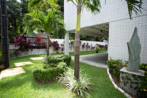 a garden with palm trees and plants in front of a building at FLAT BOA VIAGEM PRÓXIMO A PRAIA in Recife