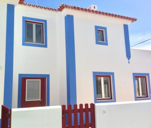 a white and blue house with a red fence at Casa da Âncora - Comporta in Comporta