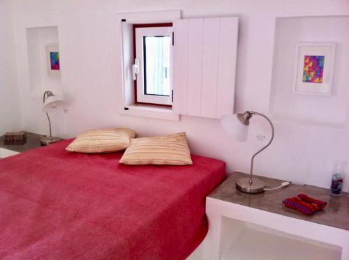 a bedroom with a red bed with a window at Casa da Âncora - Comporta in Comporta