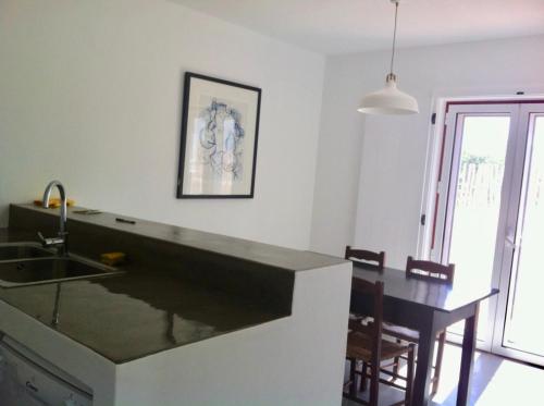 a kitchen with a sink and a table with chairs at Casa da Âncora - Comporta in Comporta