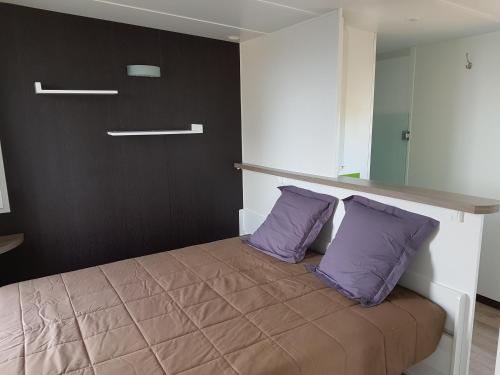 - une chambre avec un lit et 2 oreillers violets dans l'établissement Village Guerzaille, à Saint-Caradec