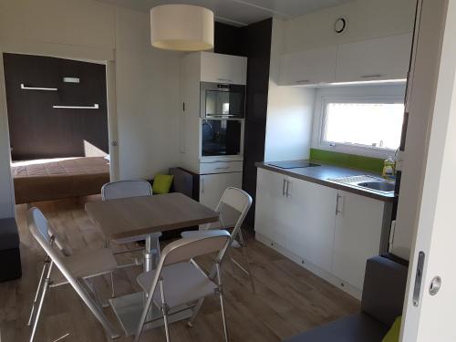 une petite cuisine et salle à manger avec une table et des chaises dans l'établissement Village Guerzaille, à Saint-Caradec