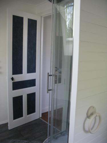 a glass shower door next to a white wall at La maison in Tarnac