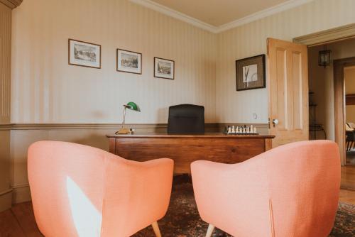 two orange chairs in a room with a desk at The Kitch'inn - Boutique Inn and Wine Bar in Mahone Bay