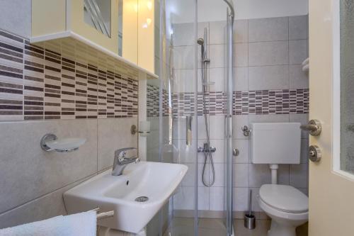 ein Bad mit einem Waschbecken, einer Dusche und einem WC in der Unterkunft SheShe in Mali Lošinj