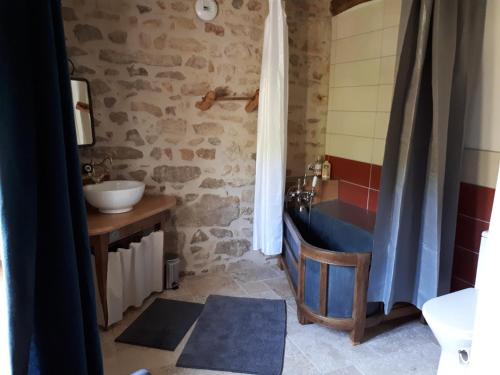 uma casa de banho com um lavatório e uma banheira num quarto em La Pierre du Grain em Ravel