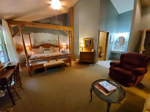 a bedroom with a bed and a chair and a table at The Barn Inn Bed and Breakfast in Millersburg