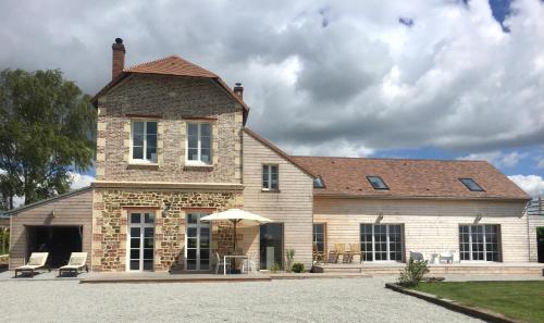 a large brick building with chairs and an umbrella at Galerie, Tumulus de la Hogue in Fontenay-le-Marmion